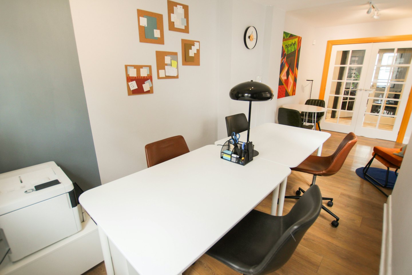 Bureau de coworking moderne avec tables blanches et notes colorées sur des tableaux en liège.