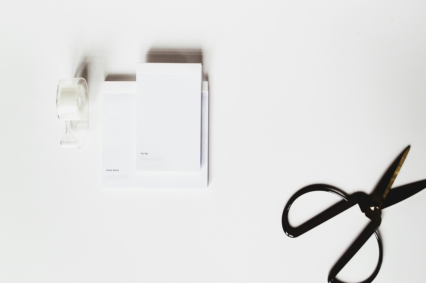 Fournitures de bureau, y compris des ciseaux et un dévidoir de ruban adhésif, sur une surface blanche.